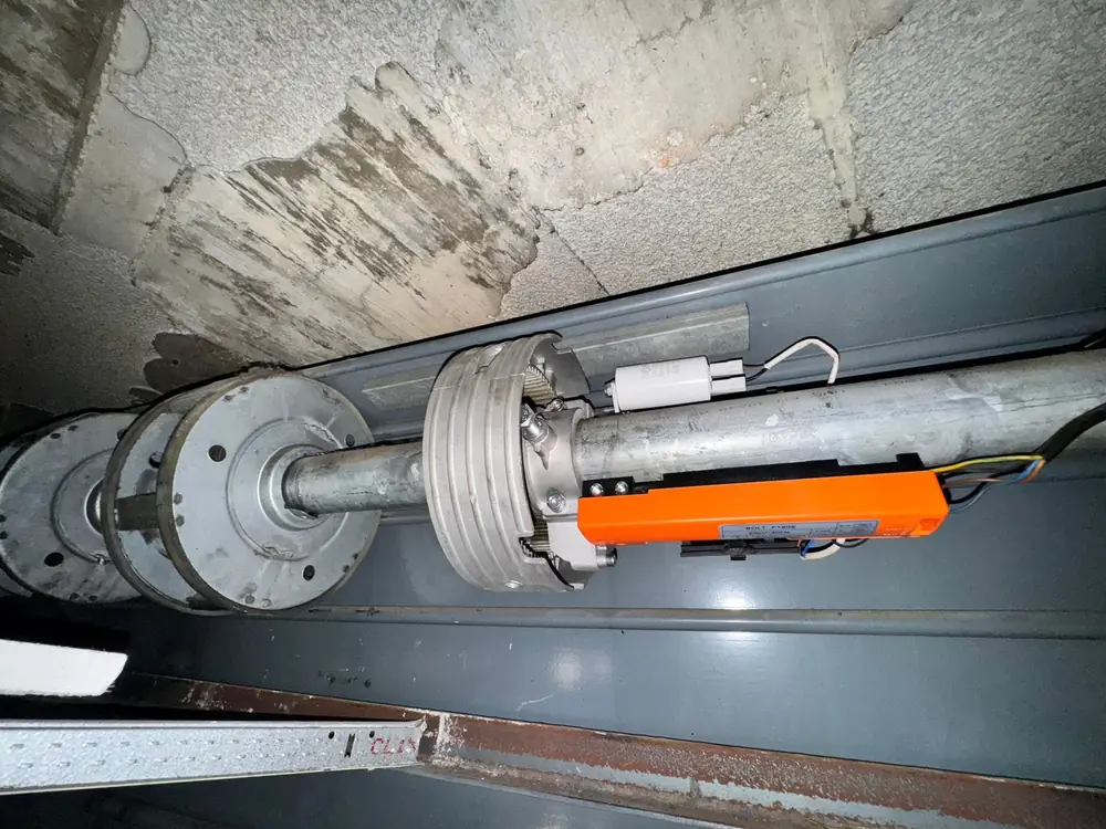 Eje de persiana metálica ya motorizado, con el motor montado y el cableado recogido