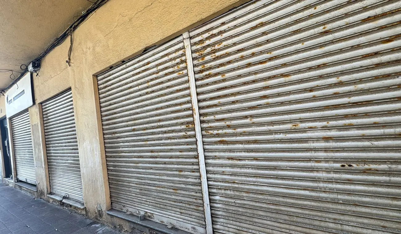 Fila de cierres metálicos de comercio en una calle de Barcelona, con la chapa envejecida